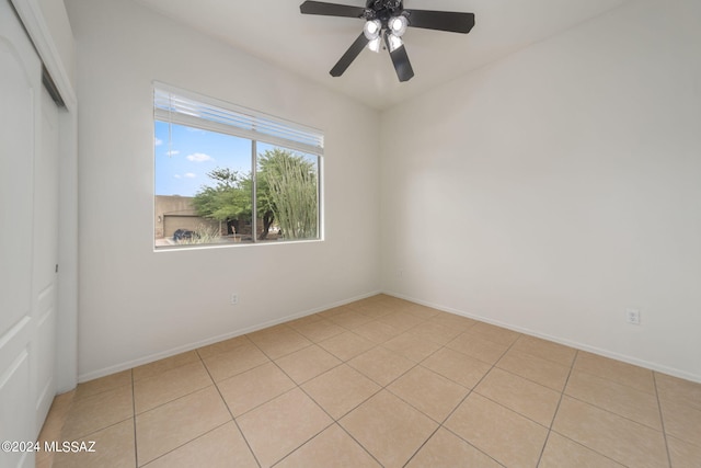 empty room with baseboards, ceiling fan, and light tile patterned floors
