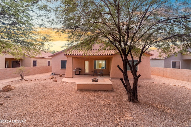 rear view of property featuring a tiled roof, a fenced backyard, a patio area, and stucco siding