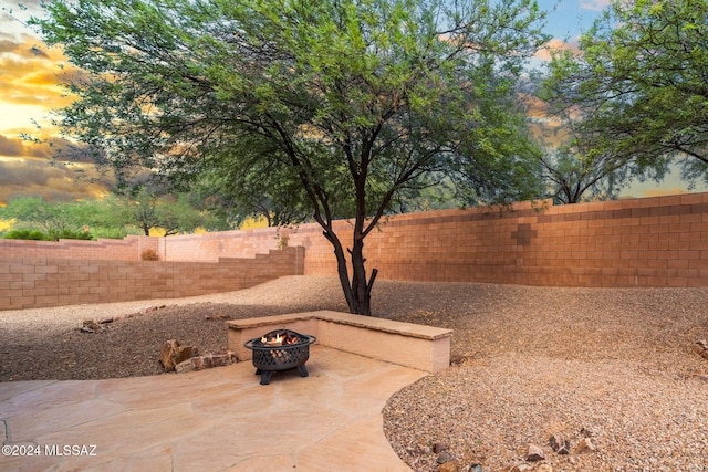 yard at dusk with a patio, a fenced backyard, and an outdoor fire pit
