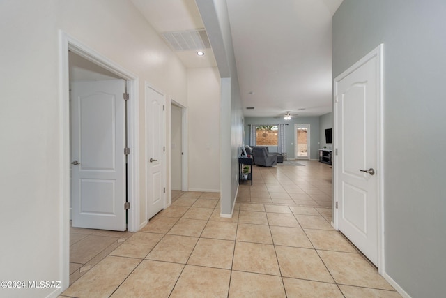 hall with visible vents, baseboards, and light tile patterned flooring
