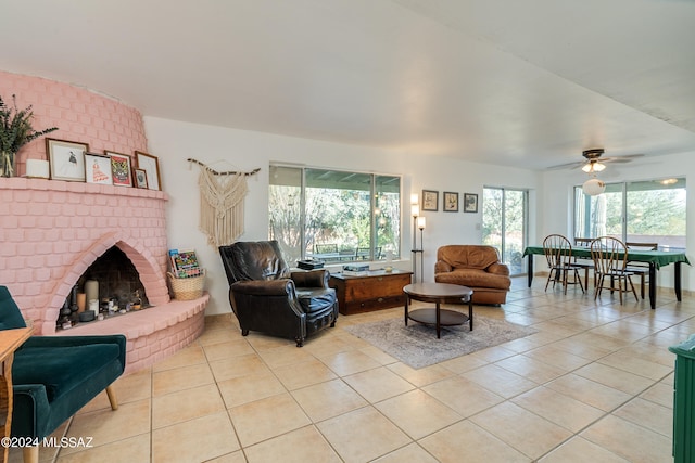 tiled living room featuring a brick fireplace and ceiling fan