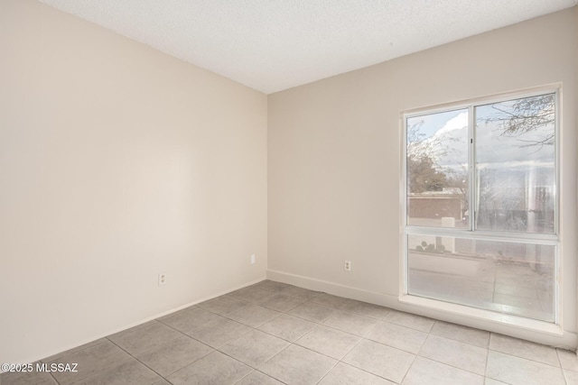 tiled spare room featuring a textured ceiling