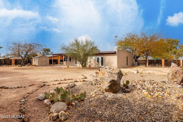 rear view of property with a storage unit and a patio area