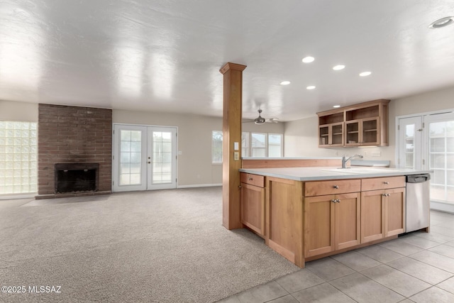 kitchen with sink, light colored carpet, dishwasher, ceiling fan, and a fireplace