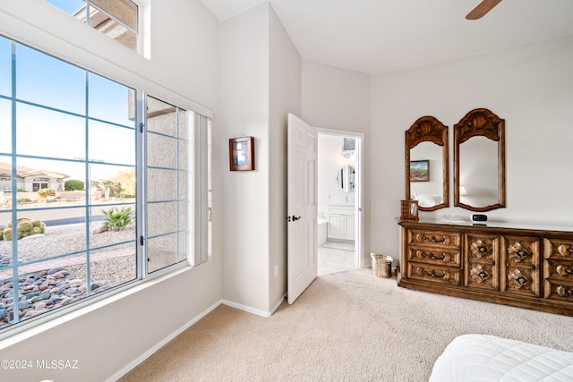 bedroom featuring ensuite bath, light colored carpet, and multiple windows