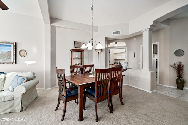 carpeted dining room with ceiling fan with notable chandelier