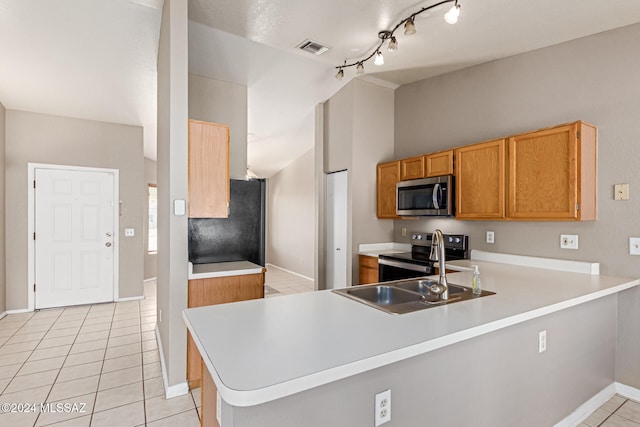 kitchen with lofted ceiling, kitchen peninsula, sink, light tile patterned floors, and appliances with stainless steel finishes