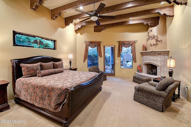 bedroom with beamed ceiling, ceiling fan, light colored carpet, and a tiled fireplace