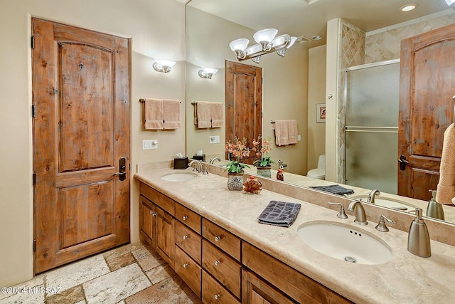 bathroom featuring toilet, vanity, a shower with shower door, and a notable chandelier