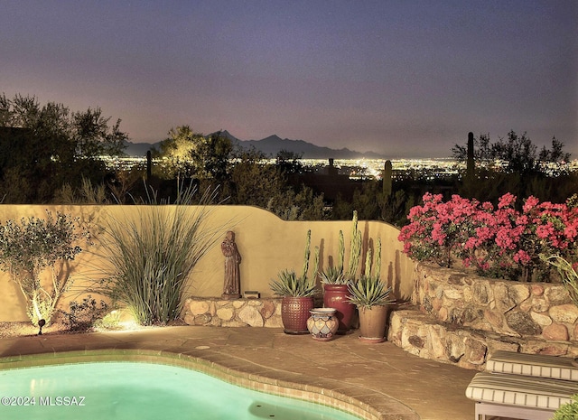 pool at dusk featuring a mountain view and a patio area