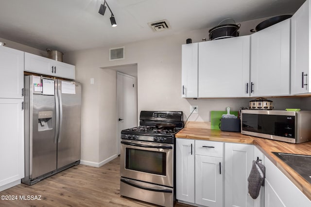 kitchen featuring appliances with stainless steel finishes, sink, butcher block countertops, white cabinetry, and light hardwood / wood-style floors