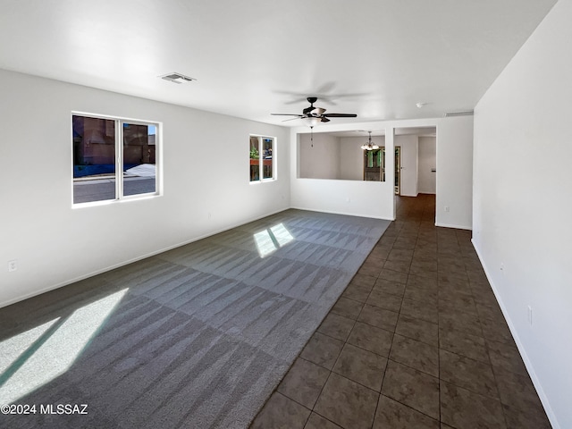 unfurnished living room with ceiling fan and dark tile patterned flooring