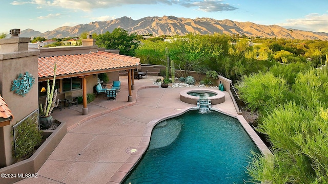 view of pool featuring a mountain view, a patio, and an in ground hot tub