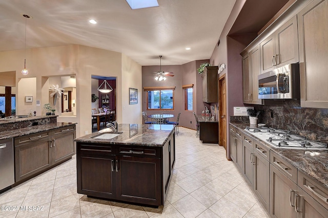 kitchen featuring stainless steel appliances, sink, hanging light fixtures, and dark stone counters