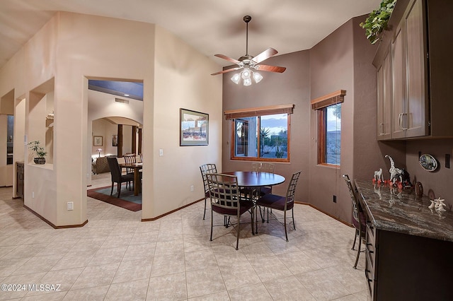 tiled dining area featuring ceiling fan and a high ceiling