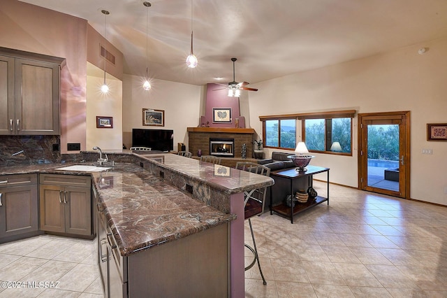 kitchen featuring tasteful backsplash, sink, dark stone countertops, a breakfast bar area, and hanging light fixtures