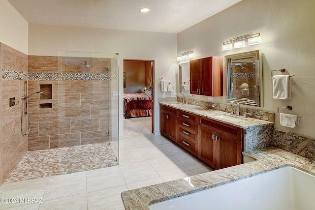 bathroom featuring tile patterned flooring, vanity, and a tile shower