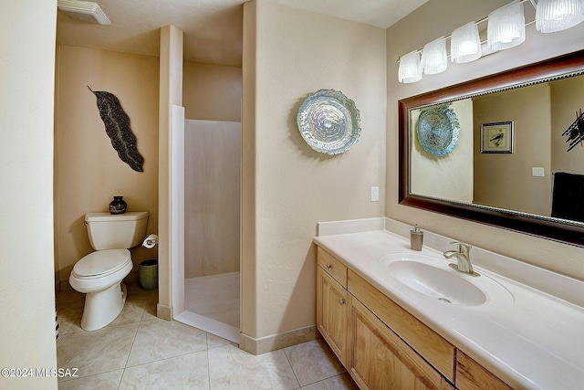 bathroom with a shower, vanity, tile patterned floors, and toilet