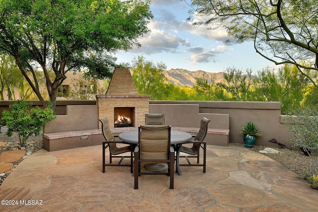 view of patio featuring a mountain view and an outdoor stone fireplace