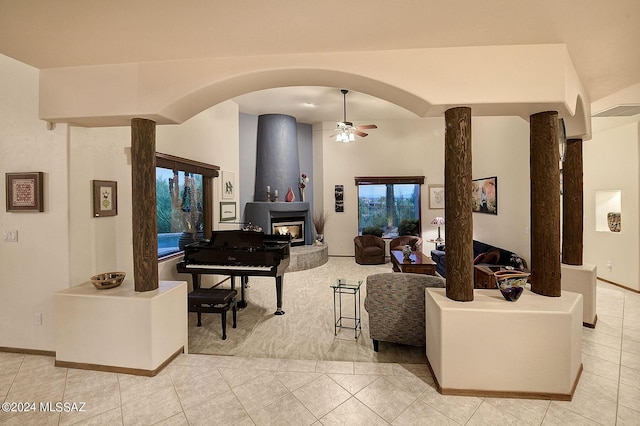 tiled living room featuring a multi sided fireplace and ceiling fan