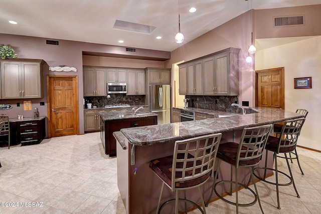 kitchen featuring pendant lighting, stainless steel appliances, kitchen peninsula, and a breakfast bar area