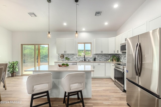 kitchen featuring stainless steel appliances, visible vents, a breakfast bar area, and decorative backsplash