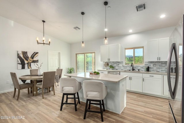 kitchen featuring visible vents, stainless steel appliances, decorative backsplash, light countertops, and a sink