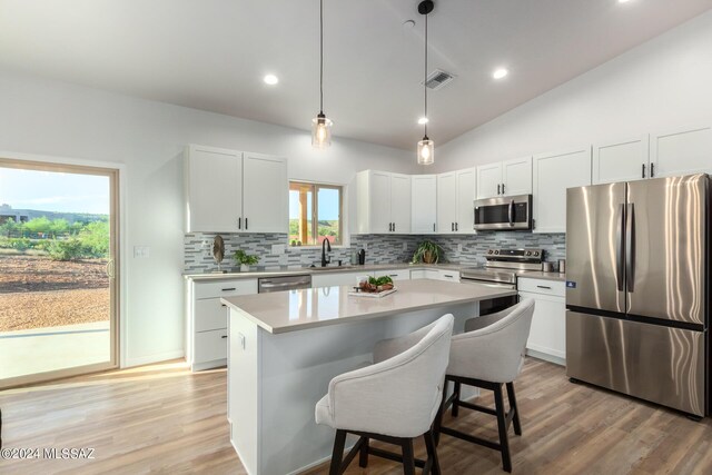 kitchen with light countertops, visible vents, stainless steel appliances, a sink, and a breakfast bar area