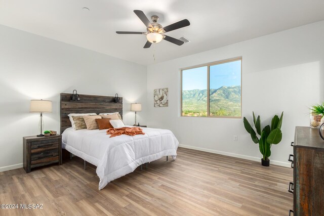 bedroom featuring baseboards, visible vents, light wood-style floors, and a ceiling fan