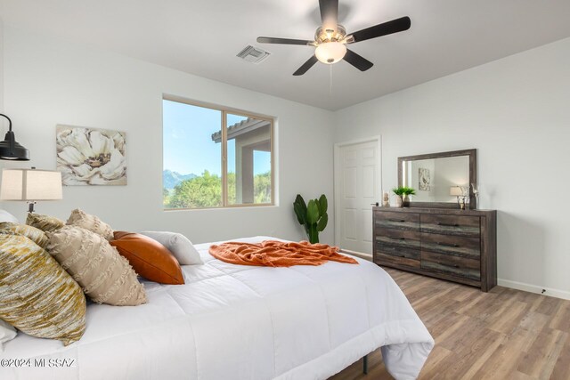 bedroom featuring baseboards, visible vents, wood finished floors, and ceiling fan