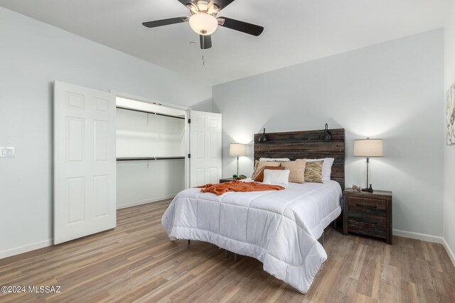 bedroom featuring baseboards, wood finished floors, a closet, and a ceiling fan