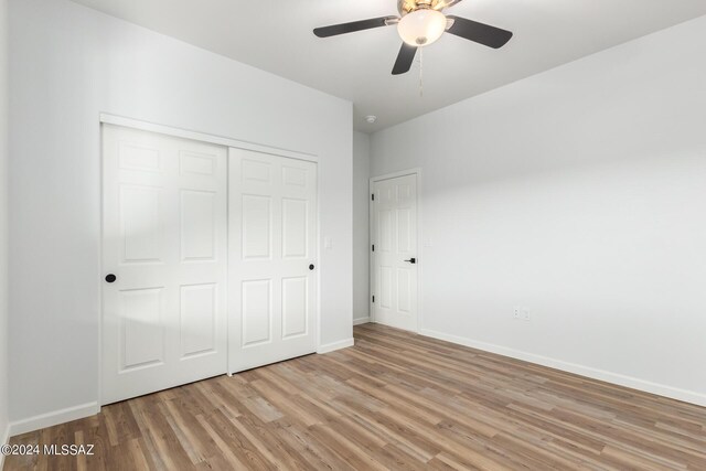 unfurnished bedroom with baseboards, a closet, light wood-style flooring, and ceiling fan