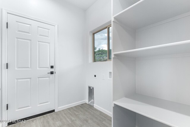 laundry room featuring baseboards, laundry area, light wood-type flooring, and electric dryer hookup