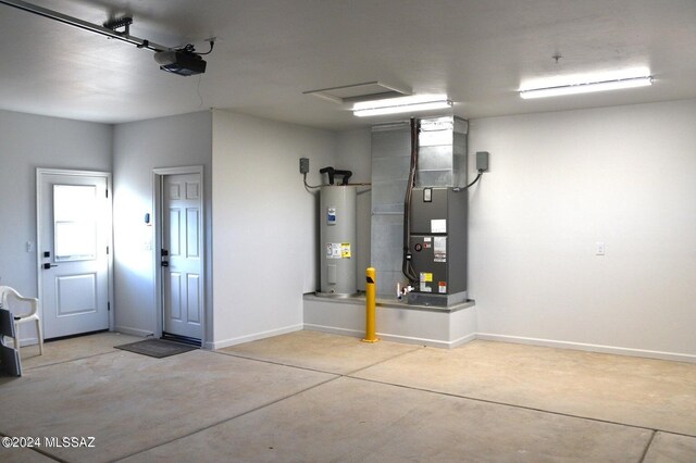 garage featuring baseboards, heating unit, electric water heater, and a garage door opener