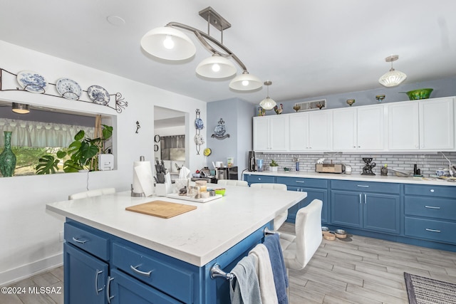 kitchen with blue cabinetry, a center island, hanging light fixtures, and white cabinets