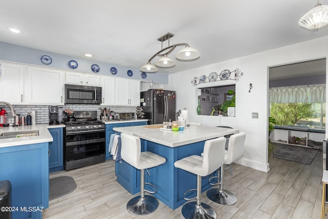 kitchen with white cabinetry, stainless steel appliances, sink, and pendant lighting