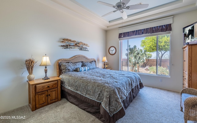 bedroom with light colored carpet, baseboards, multiple windows, and a raised ceiling