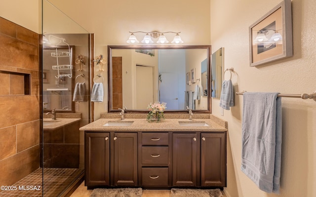 full bathroom with a sink, double vanity, and a tile shower