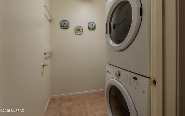laundry area with baseboards, stacked washer and clothes dryer, laundry area, and light tile patterned floors