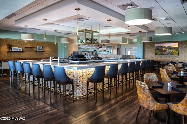 bar featuring decorative backsplash, pendant lighting, wood finished floors, and a drop ceiling