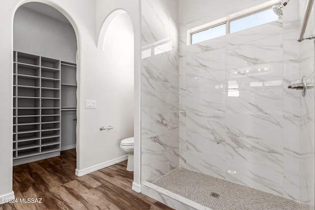 bathroom featuring toilet, hardwood / wood-style floors, and tiled shower