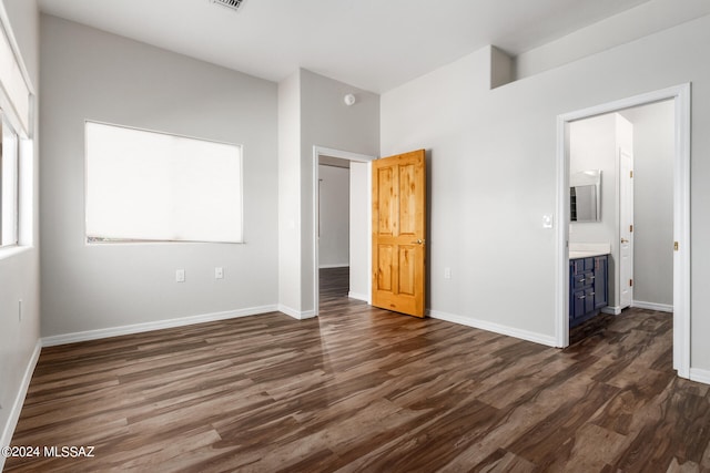 unfurnished bedroom featuring connected bathroom and dark hardwood / wood-style flooring