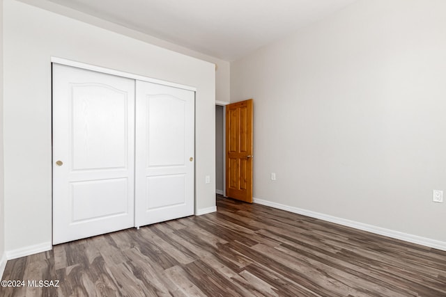 unfurnished bedroom featuring a closet and dark wood-type flooring