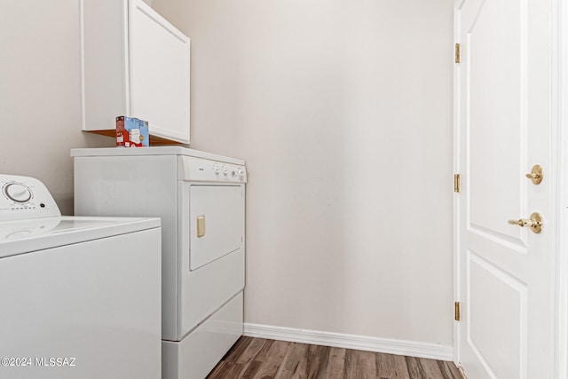 clothes washing area featuring cabinets, independent washer and dryer, and hardwood / wood-style flooring