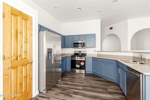 kitchen with blue cabinets, dark wood-type flooring, stainless steel appliances, and sink