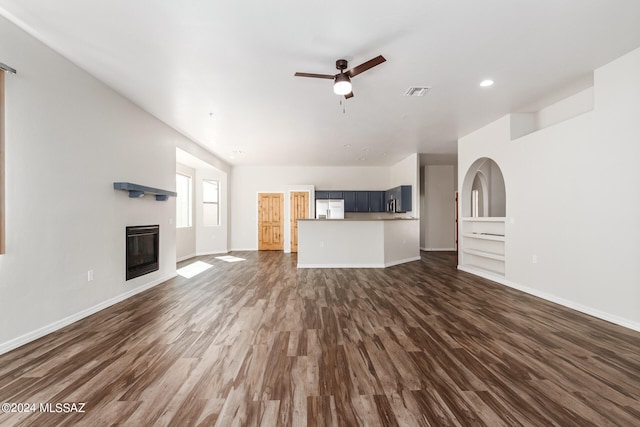 unfurnished living room featuring dark wood-type flooring and ceiling fan