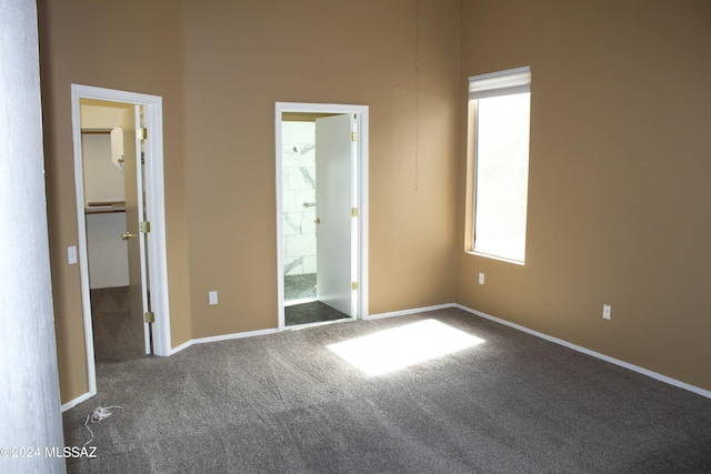 unfurnished bedroom featuring carpet floors, baseboards, a walk in closet, and connected bathroom