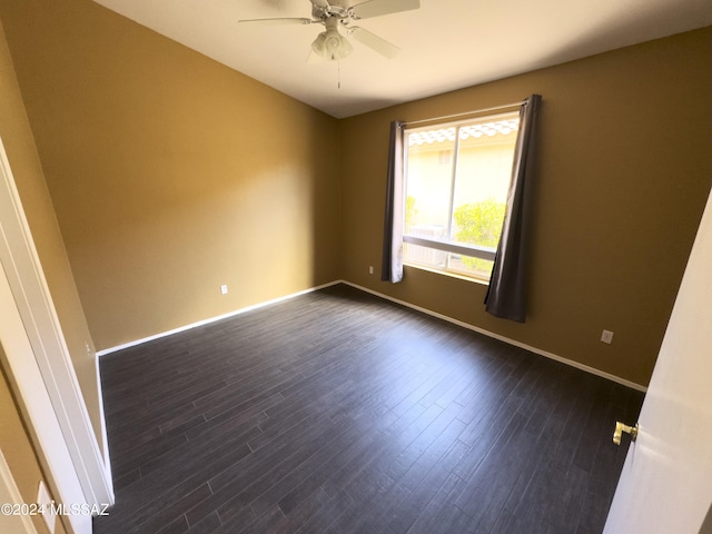 spare room featuring baseboards, ceiling fan, and dark wood-style floors