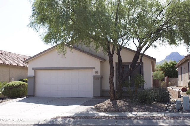 ranch-style home with concrete driveway, a garage, a mountain view, and stucco siding