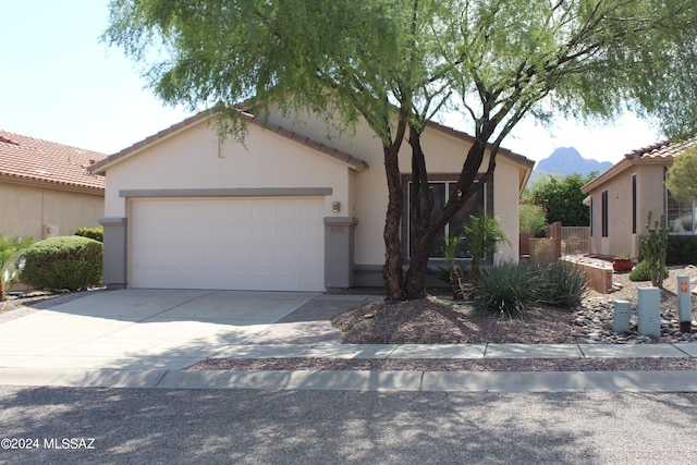 ranch-style house with driveway, a tile roof, a mountain view, an attached garage, and stucco siding